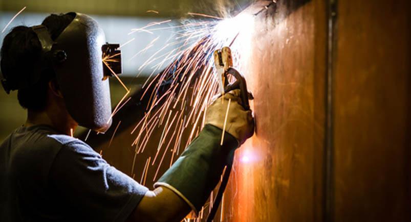 worker with protective mask welding metal and sparks Utilities worker using a torch