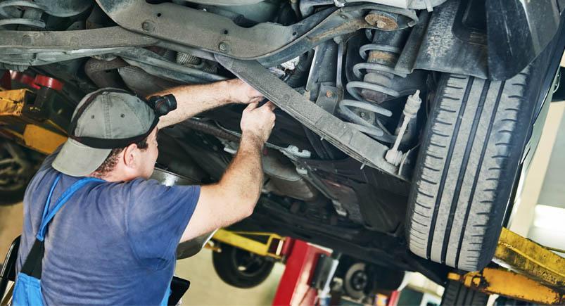 Automobile mechanic checks car suspension in service station A vehicle being operated on