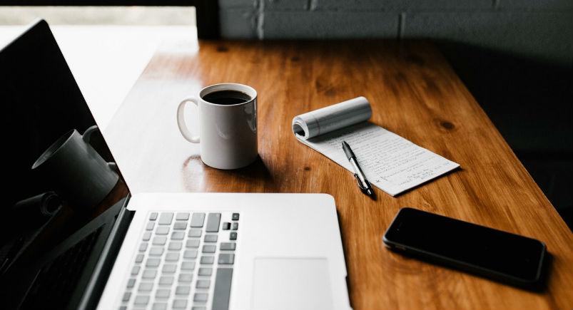 Computer, notepad, and phone on a desk