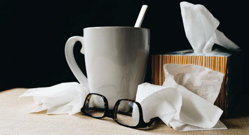 A mug, glasses, and tissues on a desk