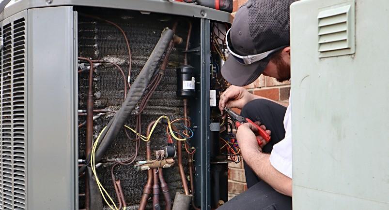 HVAC technician repairing A/C unit after receiving work order in Mobile Workforce Plus via Dropbox integration