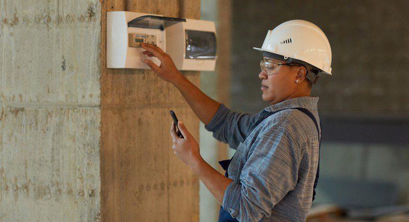 Electrician checking readings entered into the company's Mobile Workforce Management software on her device for job information