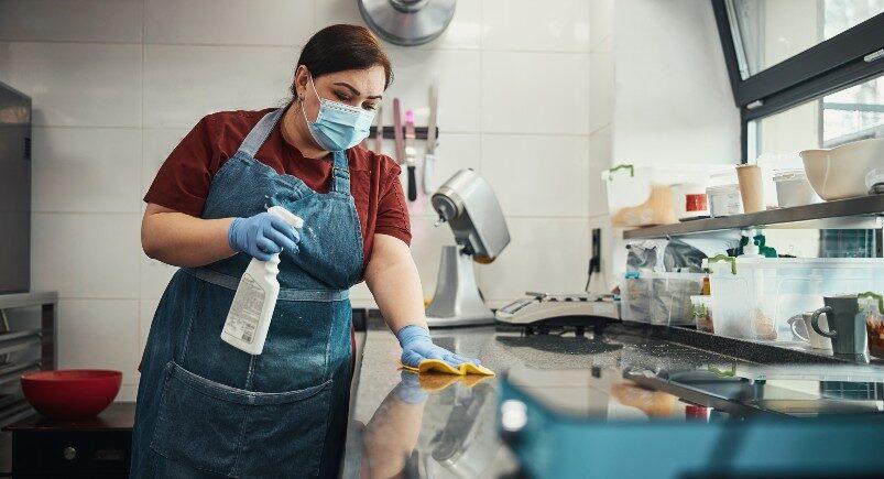 Cleaning service company employee cleaning a restaurant kitchen