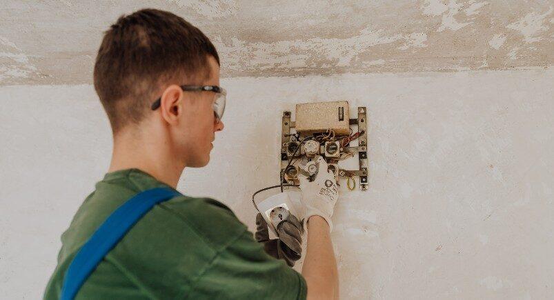 An electrician repairing an electrical panel on the wall