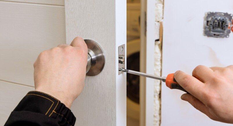 A locksmith installing a lock on a door
