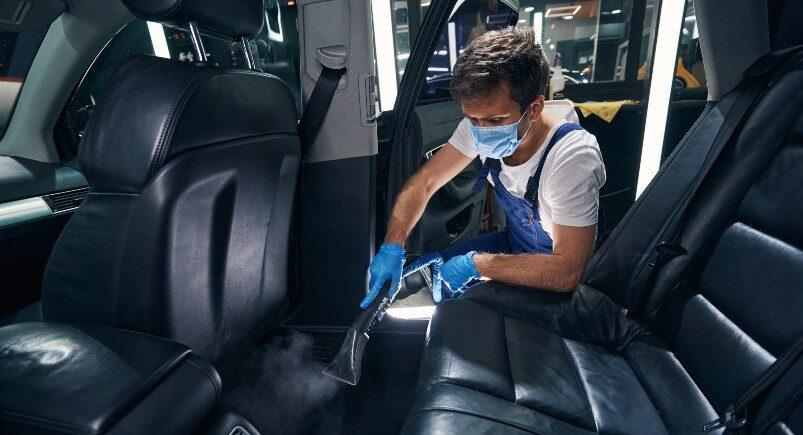 A car cleaning employee vacuuming a vehicle cabin