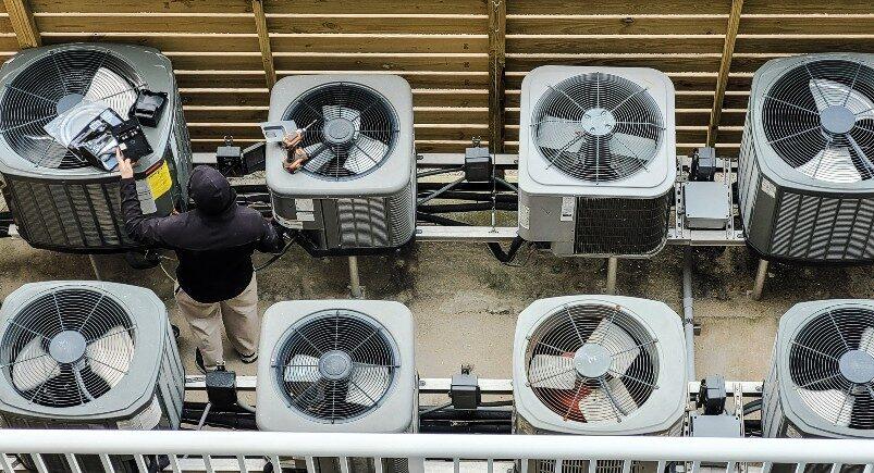 An HVAC service technician working on units