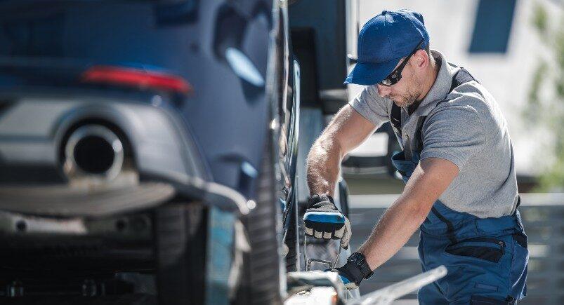 A towing company driver securing an SUV to the truck